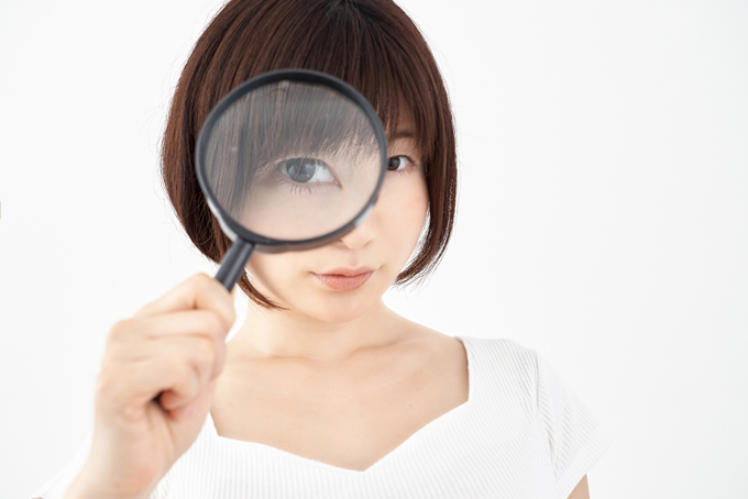 虫眼鏡を見て情報を探している女性