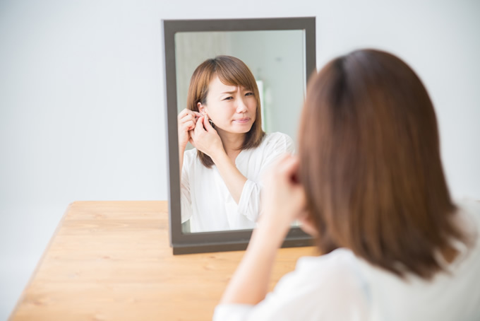 鏡で耳を見て困惑する女性