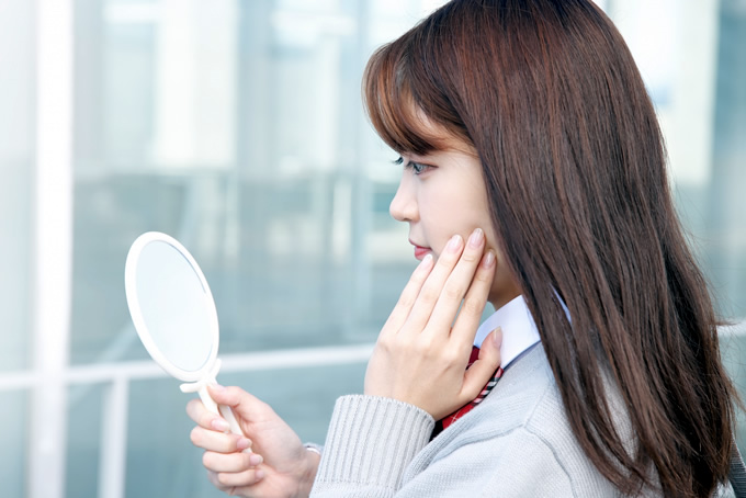 手鏡で顔を確認する女性