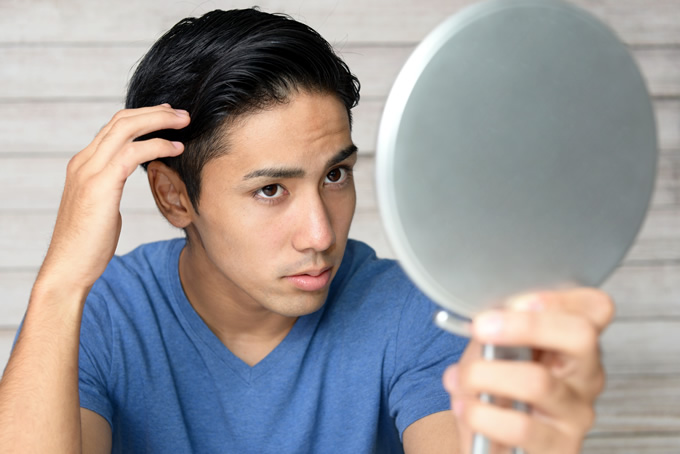 鏡で髪型を確認する短髪の男性