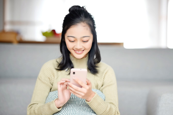 笑顔でスマホを操作する女性